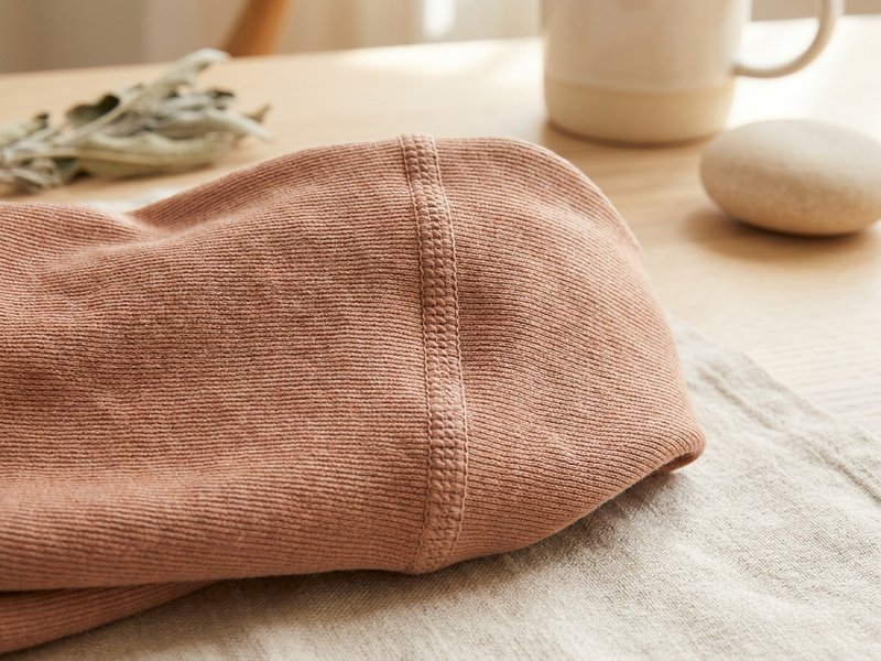 Gros plan d'un tricot de compression maille plate : tissu plus épais avec une couture visible, posé sur du lin